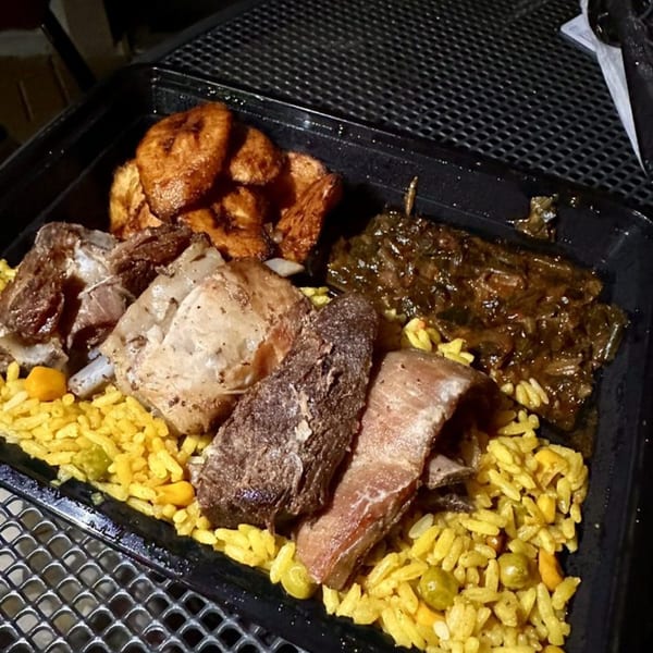 Lynda's African Delicacies meal with rice, meat, plantains, and greens in a black container.